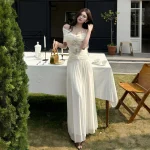 Ivory off-shoulder lace-panel maxi dress, full-length outdoor view
